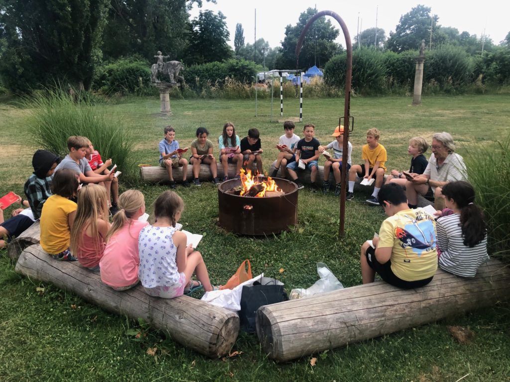 Kinder sitzen im Kreis um ein Feuer